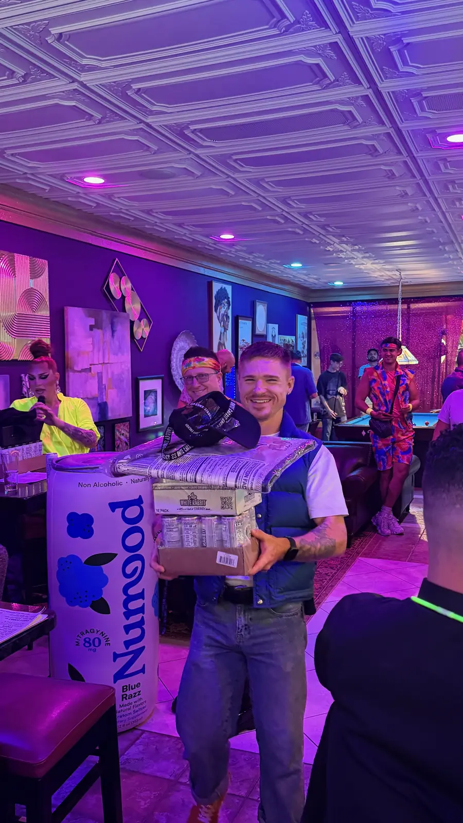 A Drag Bingo winner holding a stack of prizes
